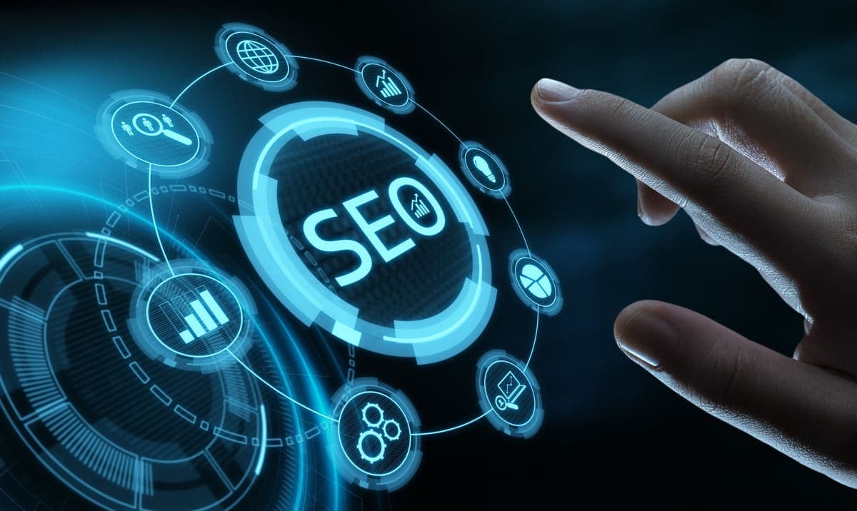 A person typing on a laptop with SEO analytics charts on the screen